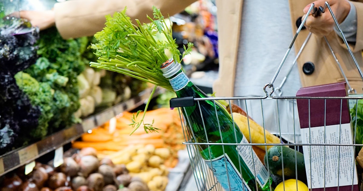 Klant met een boodschappenmand in een supermarkt vol producten