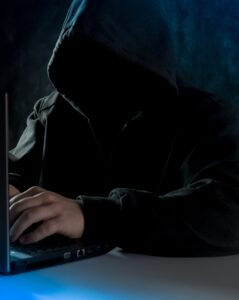 Afbeelding van duister uitziend persoon achter laptop.