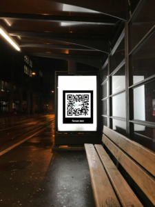Advertentiescherm bij bushalte met een QR code.